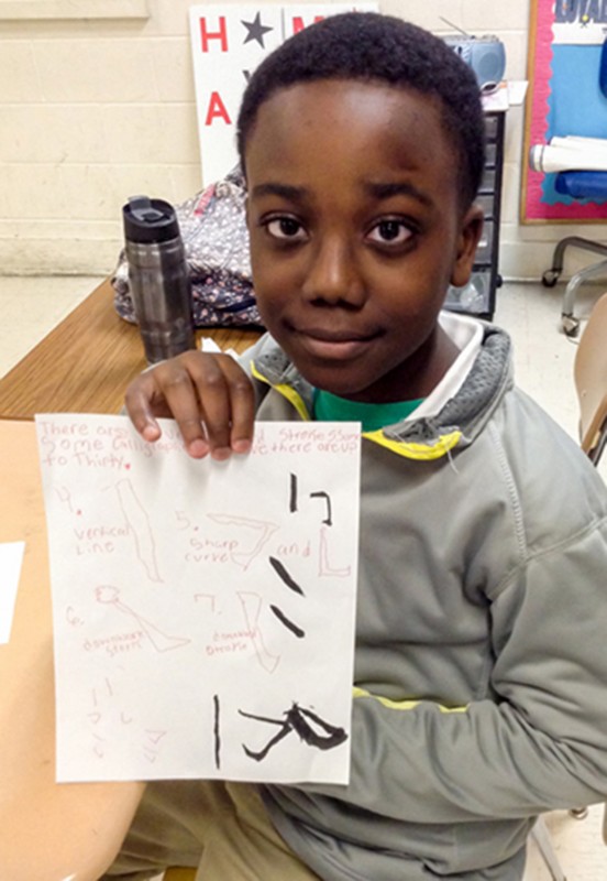 Student holds up example of Chinese calligraphy.