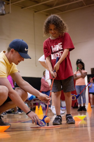 Instructor from First Tee works with a child on golf skills.