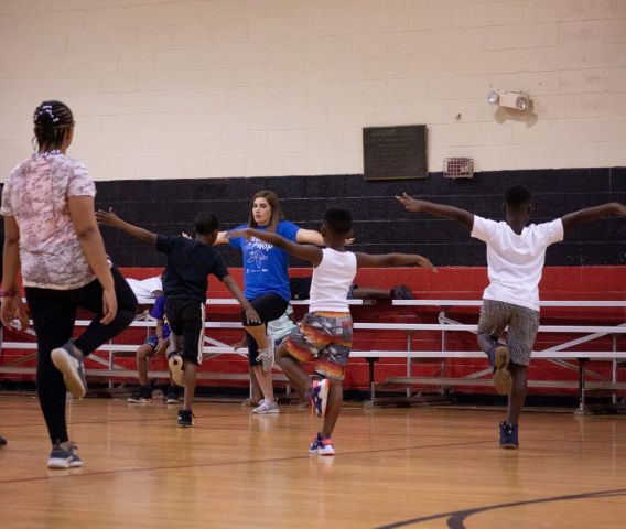 Physical education instructor Tori Ivy leads children to work on balance through yoga.