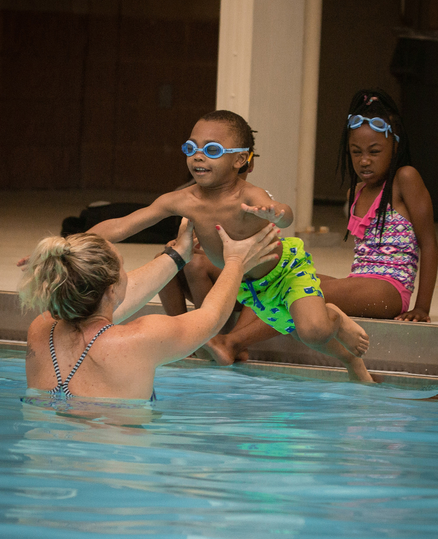 Program coordinator and swim instructor Daniela Susnara helps as a child jumps into the water.