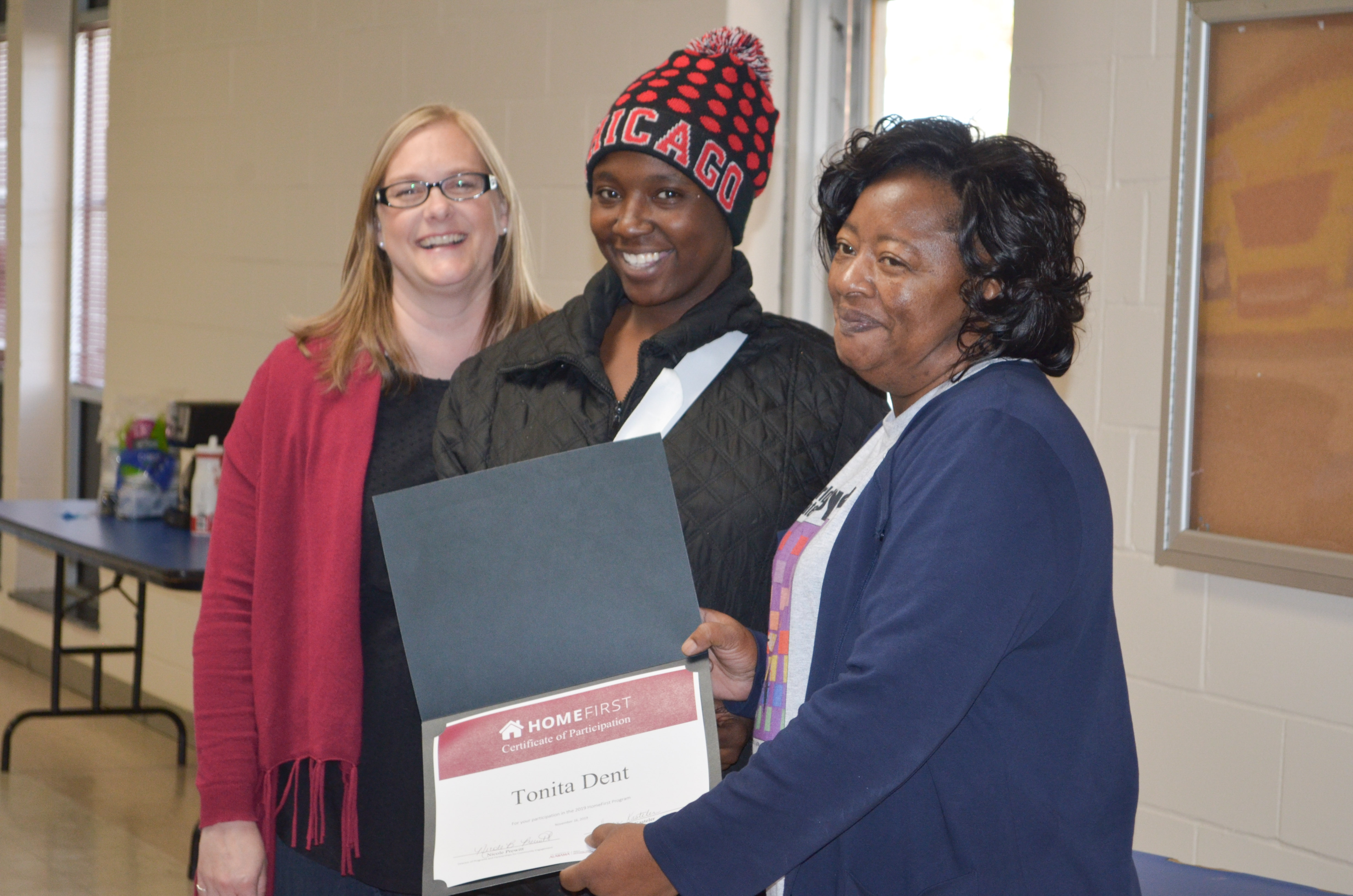 Anita Lewis, executive director of the Housing Authority of Greene County (right) and Susan Kasteler, HomeFirst program coordinator (left), present a certificate of participation to Tonita Dent.