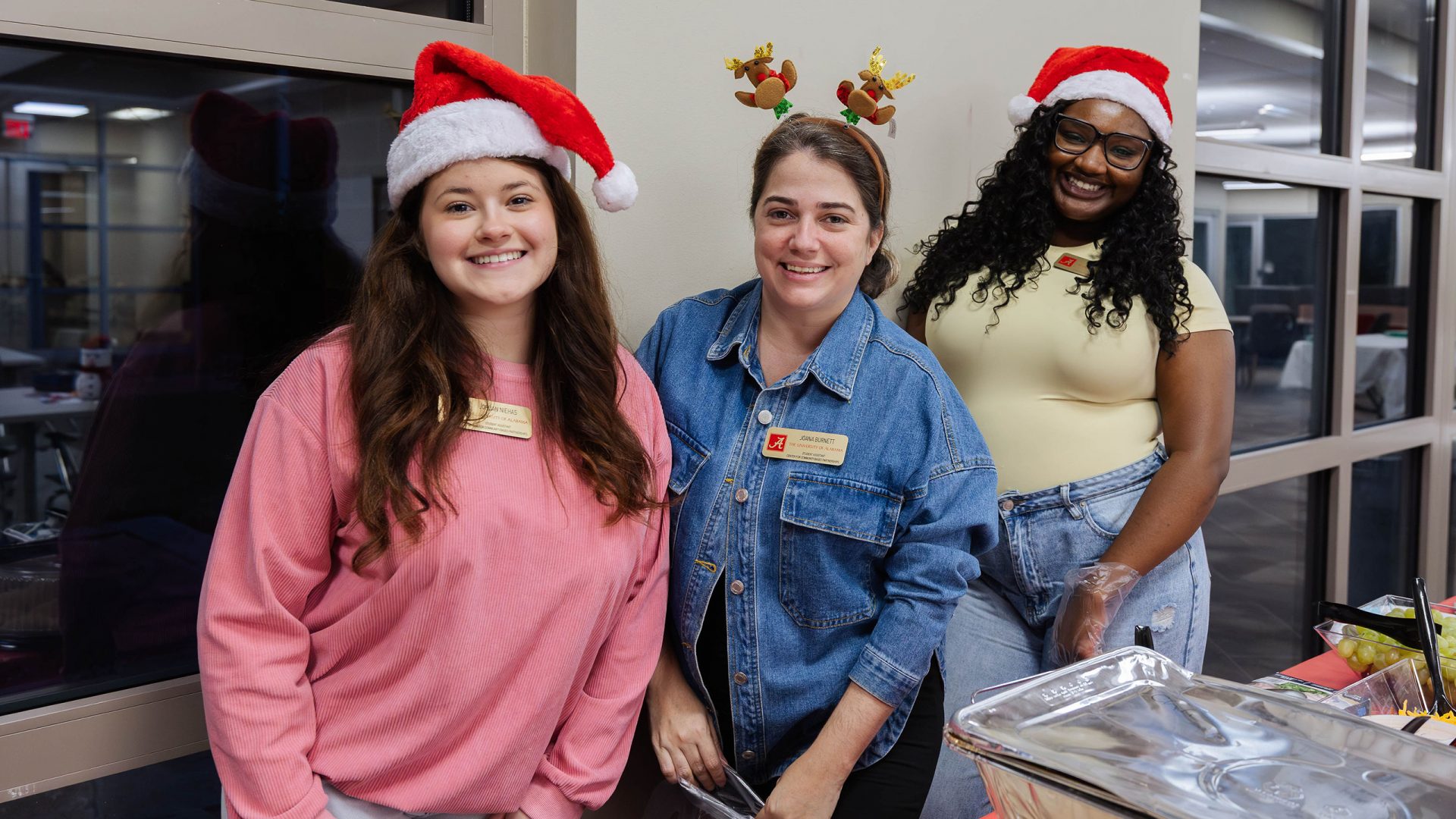 Three girls wearing holiday headwear pose for a photo at a holiday Global Café event