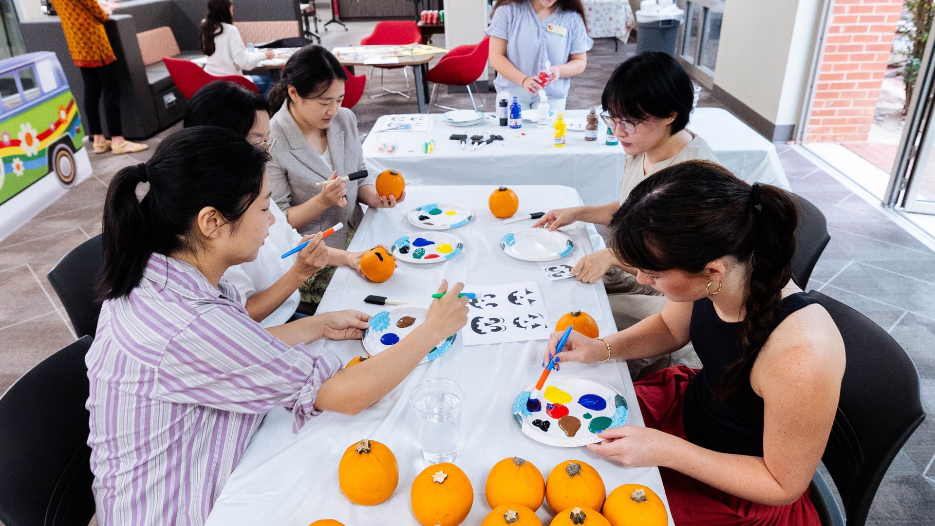 Students enjoy painting oranges at a fall Global Café event in the Student Community Engagement Center