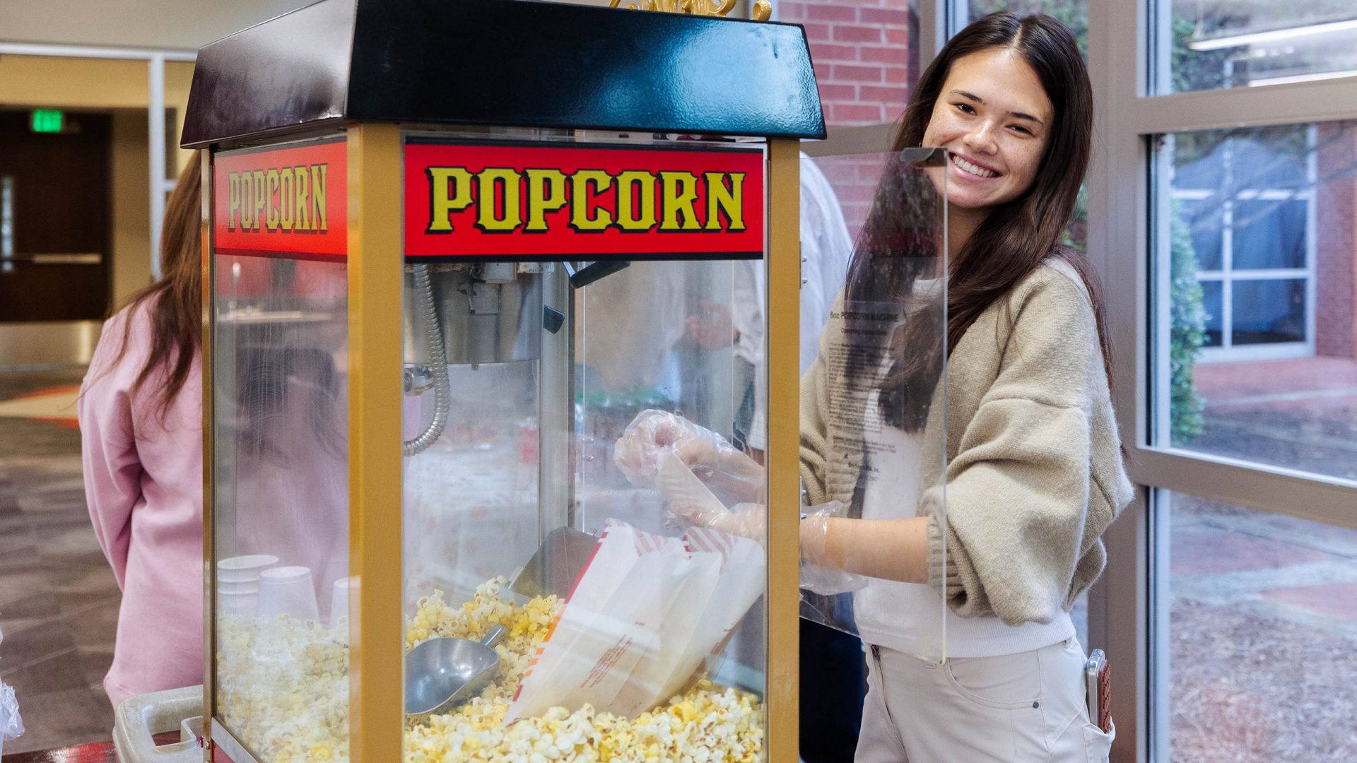 A student fills popcorn bags from a popcorn maker