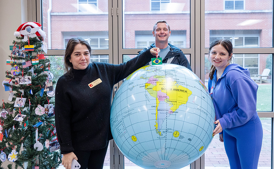 People at a Global Café event hold up an inflatable globe and point to the country they are from