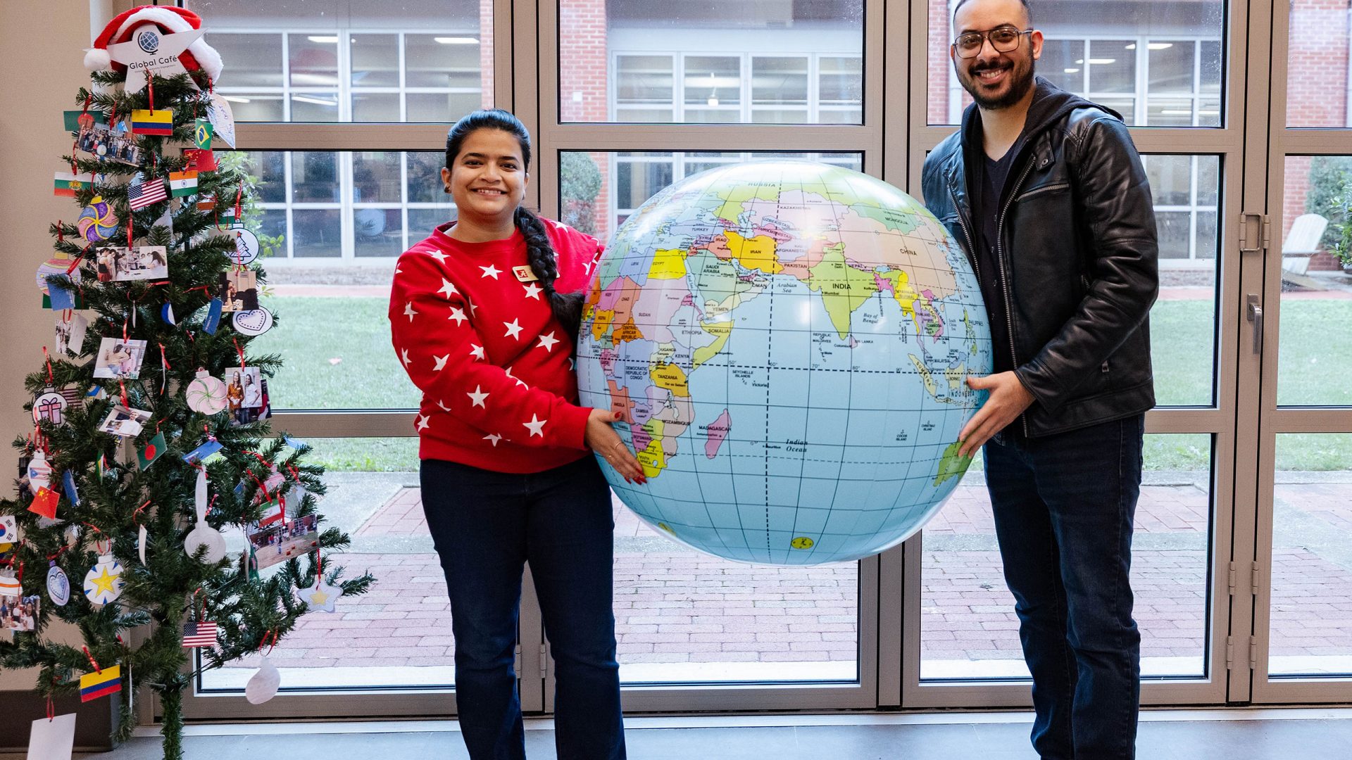 People at a Global Café event hold up an inflatable globe and point to the country they are from