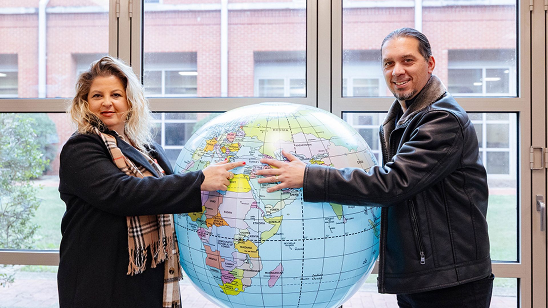 People at a Global Café event hold up an inflatable globe and point to the country they are from